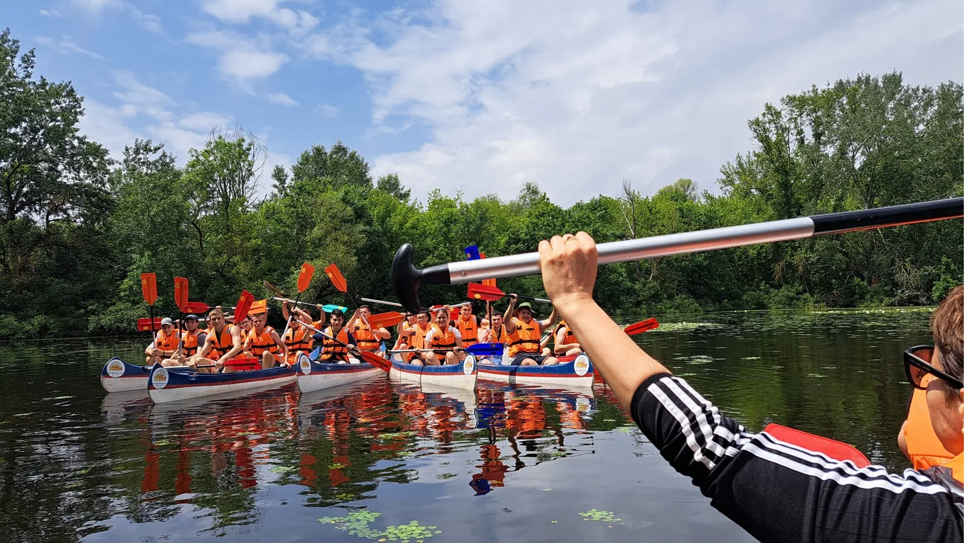 Kenus diákcsoport a vízen, előtérben egy magasba emelt evező